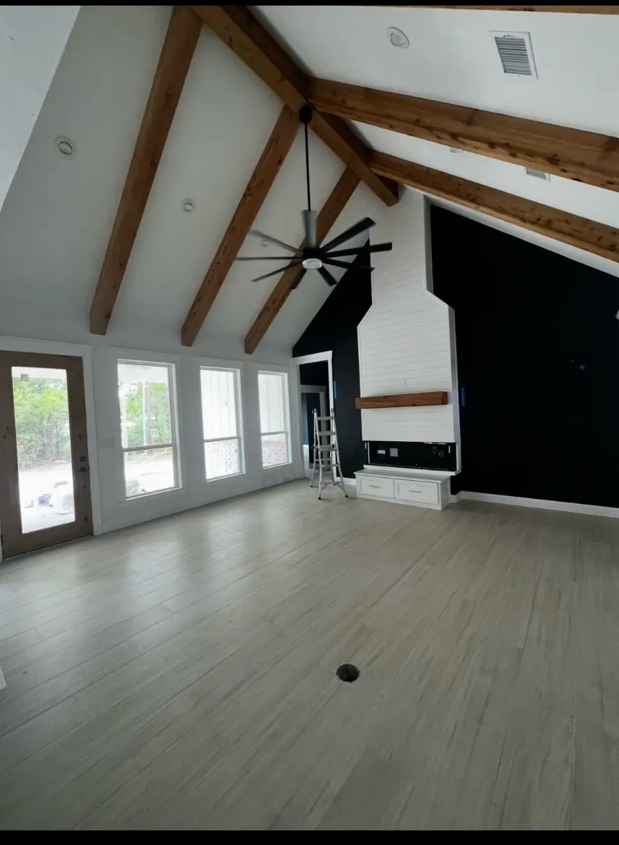 Great room with vaulted ceiling, cedar beams, and shiplap fireplace in a finished custom home