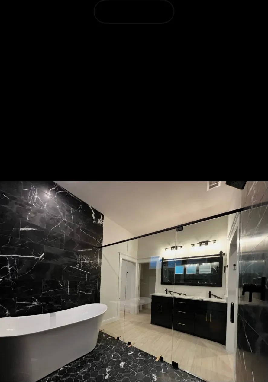 Primary bathroom with freestanding soaking tub, black marble tile, and glass shower enclosure