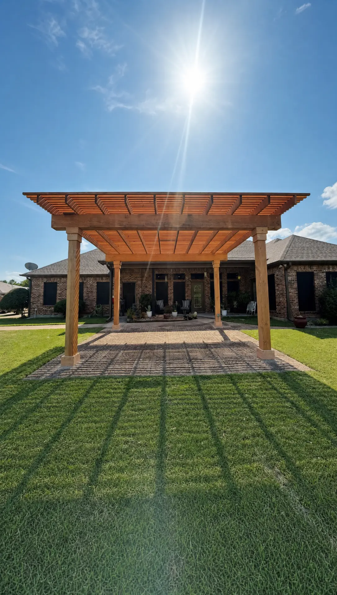 Cedar pergola over a paver patio behind a brick home, built by Elite Solutions of Texas