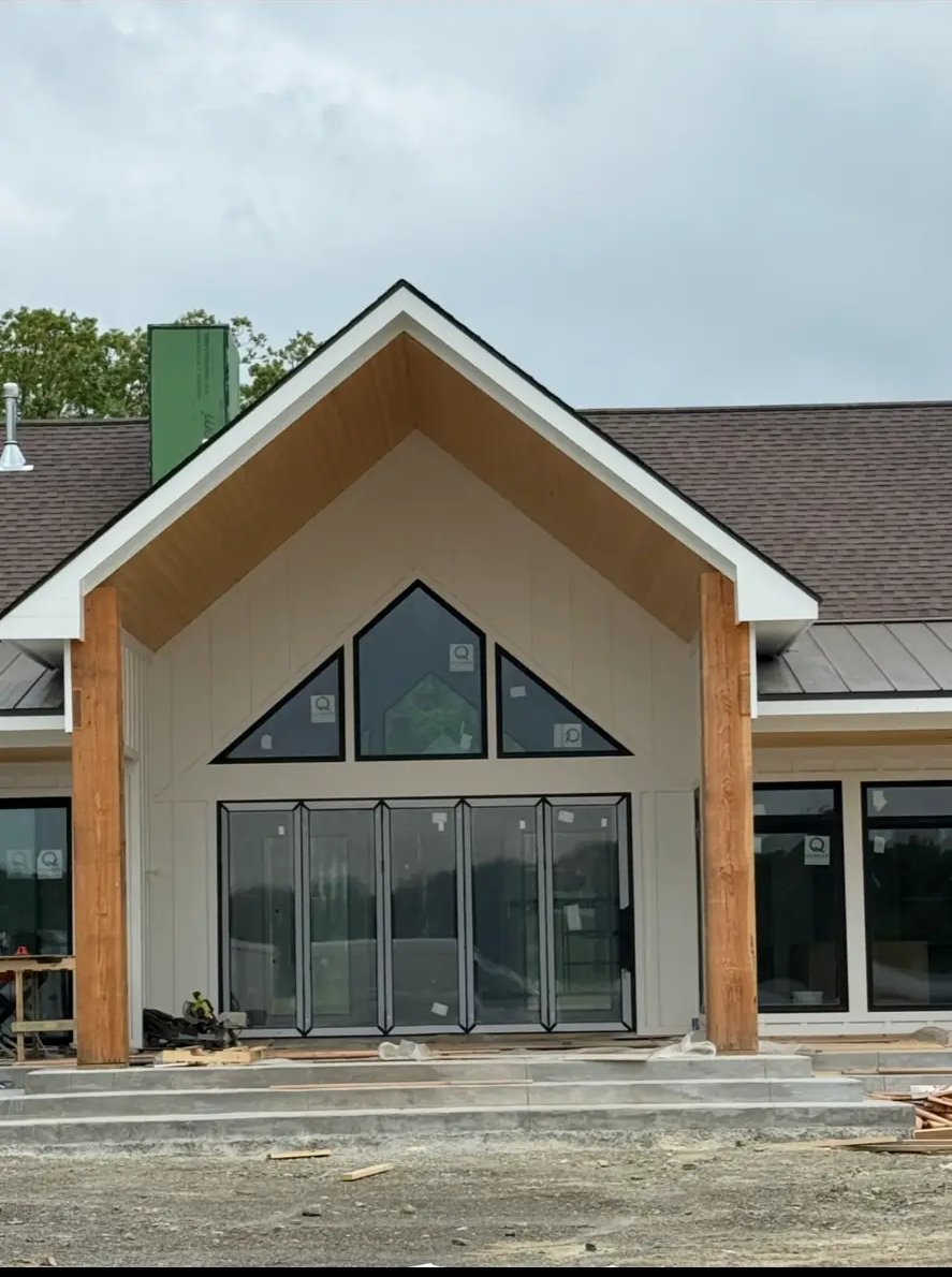 Covered gable entry with timber posts and folding glass doors under construction