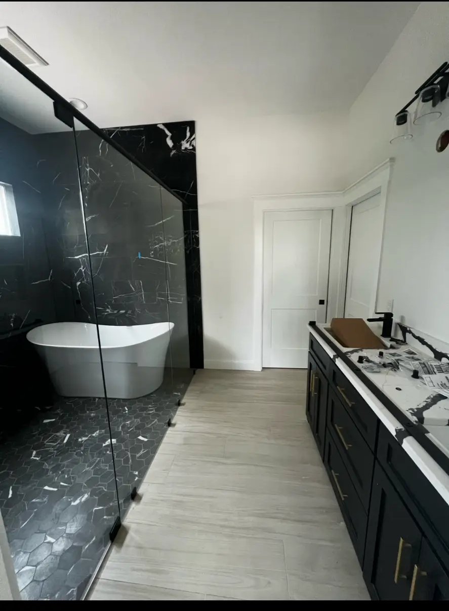 Primary bathroom with freestanding tub, black marble tile, and custom double vanity