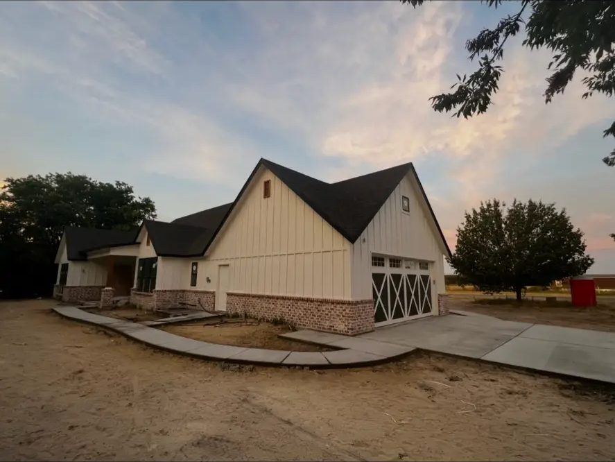 Side elevation of a finished custom home and garage on an open Northeast Texas lot