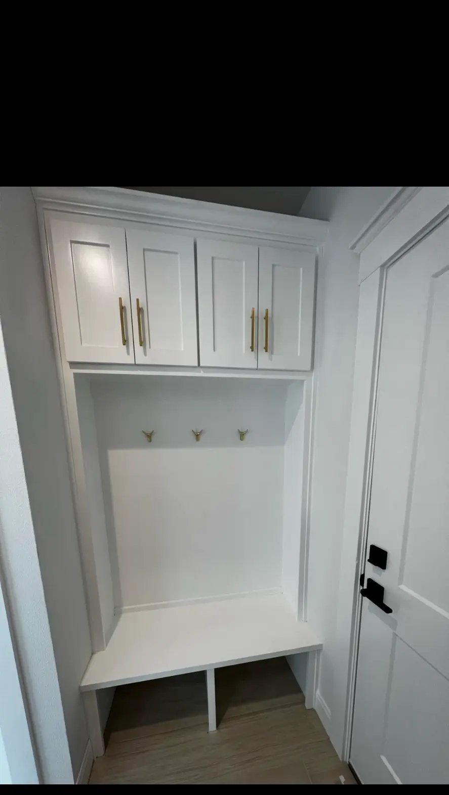 Custom mudroom bench with upper cabinets and brass hooks built by Elite Solutions of Texas